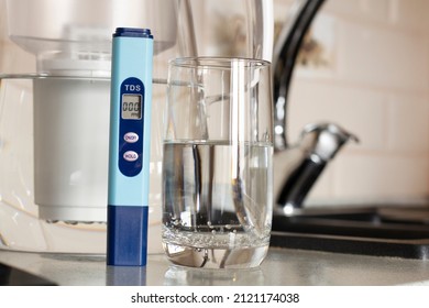 Measurement Of TDS Of Water. Electronic PH Meter In A Glass Of Water.Filter For Water Purification. There Is A Tap For Drinking Water In The Background. 