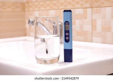 Measurement Of TDS Of Water. Electronic PH Meter In A Glass Of Water. In The Background Is A Tap For Drinking Water. Cleaning The Water In The Bathroom.