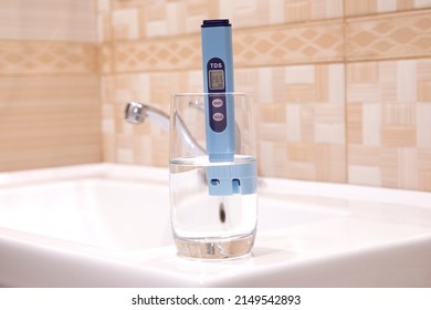 Measurement Of TDS Of Water. Electronic PH Meter In A Glass Of Water. In The Background Is A Tap For Drinking Water. Cleaning The Water In The Bathroom.