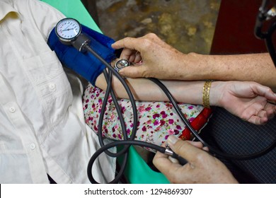 Measuring Blood Pressure Of Elder Myanmar Woman With Manual Blood Pressure Cuff By Man At Home