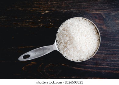 A Measuring Cup Full Of Uncooked Long Grain Rice: A Stainless Steel Measuring Cup Filled With Raw White Rice Grains