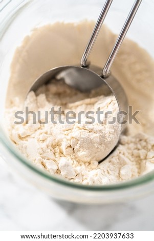 Measuring cup inside glass jar filled with all-purpose flour.
