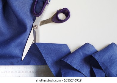 Measuring and cutting textile. Scissors and violet linen fabric. Copy space