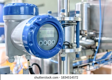 Measuring digital flowmeter. The measuring device against the backdrop of a complex system of industrial stainless pipelines.