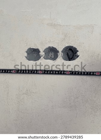 Measuring the height of an electrical socket hole with a tape measure on a plastered wall.