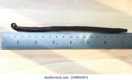 Measuring Length Of A Planifolia Madagascar Vanilla Bean On Wood Board.