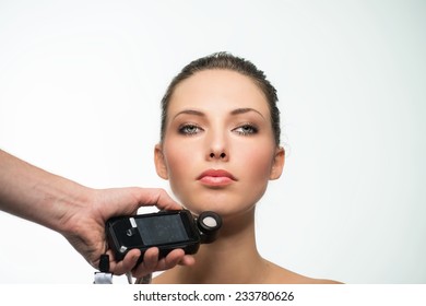 Measuring light from studio lights with flash meter close to face. Isolated against white background. - Powered by Shutterstock