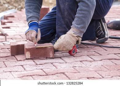 measuring and marking with a pencil on a brick paver, before CUTTING