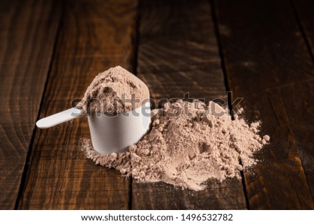 Measuring scoop of whey protein on wooden table to prepare a milkshake. Concept of diet, health and exercise