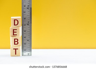 Measuring size of debt, public debt market measurement, financial concept : Cubes of debt and a ruler scale, depicts debt level debtor owes its creditor, debt is reduced by restructuring, refinancing