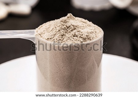 Measuring spoon with creatine or whey, on precision scale, preparing food supplement or casein cocktail, muscle mass vitamin