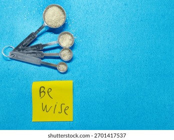 Measuring spoons filled with sugar and note “be wise” highlight portion control and awareness for world diabetes day