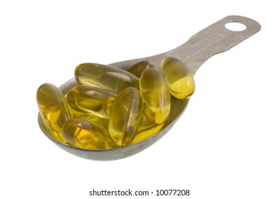 Measuring Tablespoon Of Yellow Fish Oil Capsules Isolated On White