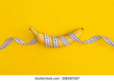 Measuring tape and banana on yellow background. Weight loss concept