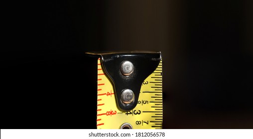 Measuring Tape End Isolated On Dark Background.  High Resolution Macro View Of Imperial Measurement System Tape, Showing Fractions Of Inches.  Wide Format With Room For Text On Either Side.