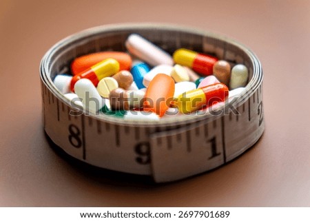 A measuring tape forms a circular container filled with a variety of colorful pills and capsules. Diet pills, weight loss supplements, and medical dosage control concepts.