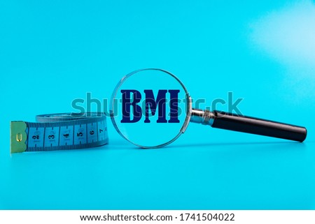 Measuring tape and magnifier with BMI Body Mass Index inscription on a blue background.