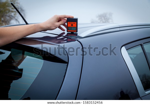 Measuring the thickness of the car paint\
coating in black color using a paint thickness\
gauge.