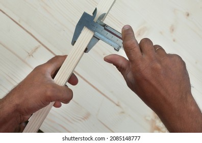 Measuring with vernier calipers (callipers). Joiner's (carpenter's) tool. Woodworking instrument. Close-up.