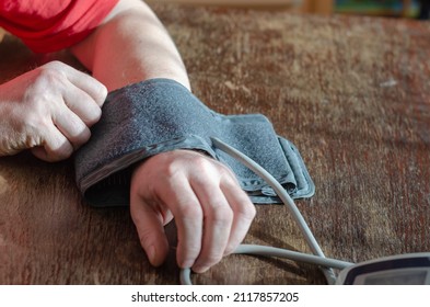 Measuring Your Blood Pressure At Home. An Adult Male Puts A Digital Blood Pressure Monitor Cuff On His Forearm. Inside The Room. Selective Focus.