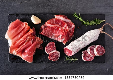 Meat appetizer platter with sausage, and Italian cold cuts. Above view on a slate serving board.