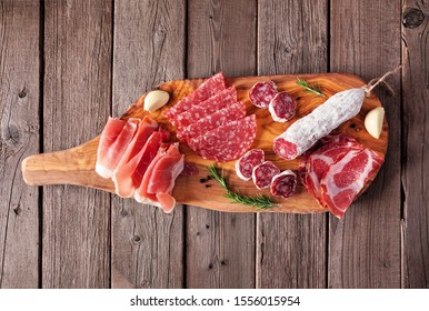 Meat appetizer platter with sausage, prosciutto, ham and salami. Top view on a serving board against a wood background. - Powered by Shutterstock