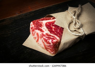 Meat From A Butcher Shop Wrapped In Paper. A Piece Of Marbled Beef In The Form Of A Rib Eye Steak. Steak For Dinner For A Loved One.