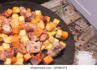 Meat, carrot and swede dice, on a stone plate. near herbs and season