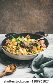 Meat Dinner. Braised Beef Meat With Potato And Carrot With Fresh Parsley In Cooking Pan Over White Marble Table Background, Selective Focus, Copy Space. Comfort Winter Food