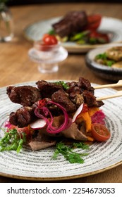 Meat dish, stake, kebab on a wooden table with salad - Shutterstock ID 2254673053