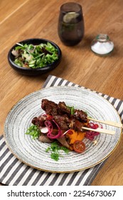 Meat dish, stake, kebab on a wooden table with salad - Shutterstock ID 2254673067