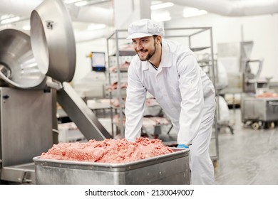 A meat factory worker pushing ground beef in container. - Powered by Shutterstock