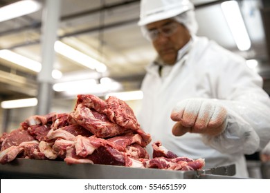 Meat Food Handling Safety Gloves And Suit With Mask Over Pile Of Raw Meat