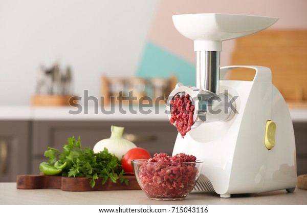 Meat\
grinder with fresh forcemeat on kitchen\
table