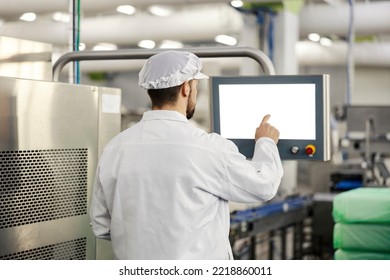 A meat industry worker programs a packing machine and types on the display.
