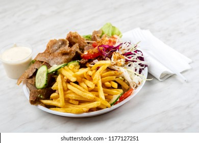 meat with kebab, French fries and salad on a plastic plate