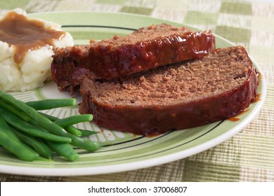 Meat Loaf Prepared With Ground Beef, Grated Carrots, Bread Crumbs, And Herbs And Spices. Served With Fresh Green Beans, Mashed Potatoes, And Gravy.