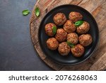 Meat meatballs in a black plate on a wooden board. Top view, copy space.
