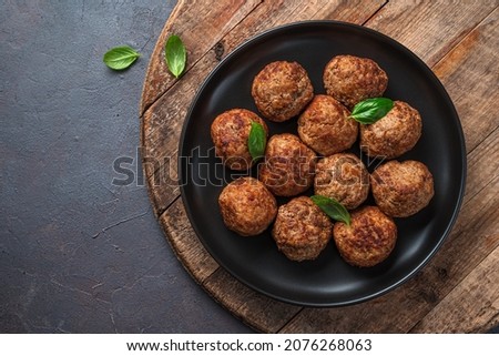 Meat meatballs in a black plate on a wooden board. Top view, copy space.