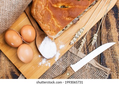 Meat Pie On A Wooden Table, Eggs And Flour Next To The Pie. View From Above