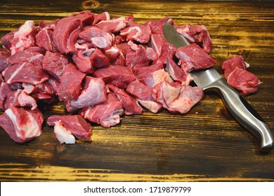 Сhopped meat in pieces. Fresh chopped beef with knife on wood background. - Shutterstock ID 1719879799