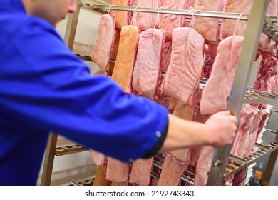 A Meat Processing Plant Worker Pulls A Cart With Meat Tenderloin And Salmon. Food Production Of Meat Products.