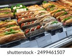 meat sandwiches and vegan sandwiches on display at a coffee shop, Street food. fast food. display case with pastries and sandwiches