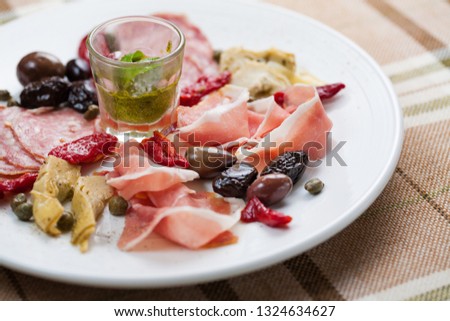Meat snacks with dried tomatoes, pesto and olives. Anti pasta platter with prosciutto, salami, capers and olives Stock photo © 