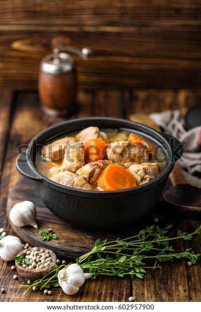 Meat stewed with carrots in\
sauce and spices in cast iron pot on dark wooden rustic\
background