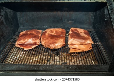 Meat Wrapped In Pink Butcher Paper Cooking On A Pellet Smoker