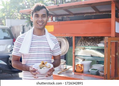 meatball street food vendor. asian man selling bakso by walking and pushing down the food carts