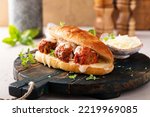Meatball sub sandwich with marinara and mozzarella and fresh herbs