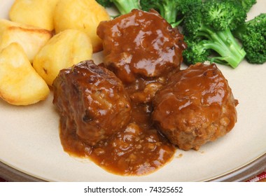Meatballs in gravy with roast potatoes and broccoli.