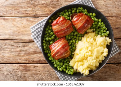 meatballs from offal fried in bacon with a garnish of green peas and mashed potatoes close-up in a plate on the table. horizontal top view from above